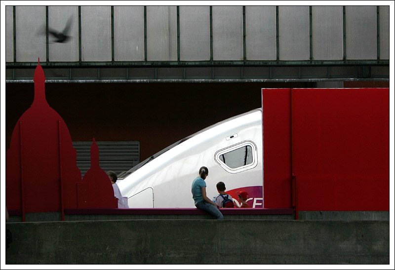 Der TGV zu seinem Vorstellungsbesuch im Stuttgarter Hauptbahnhof. Irgendwie erinnert der Zug auf dem Bild an den Kopf eines Tieres. W�hrend das Drumherum relativ dunkel ist, ist der TGV sch�n im Licht. Passend die den Zug betrachtenden Personen, st�rend die Frau links. Ein kleines Extra die Taube hinter der Milchglasscheibe.